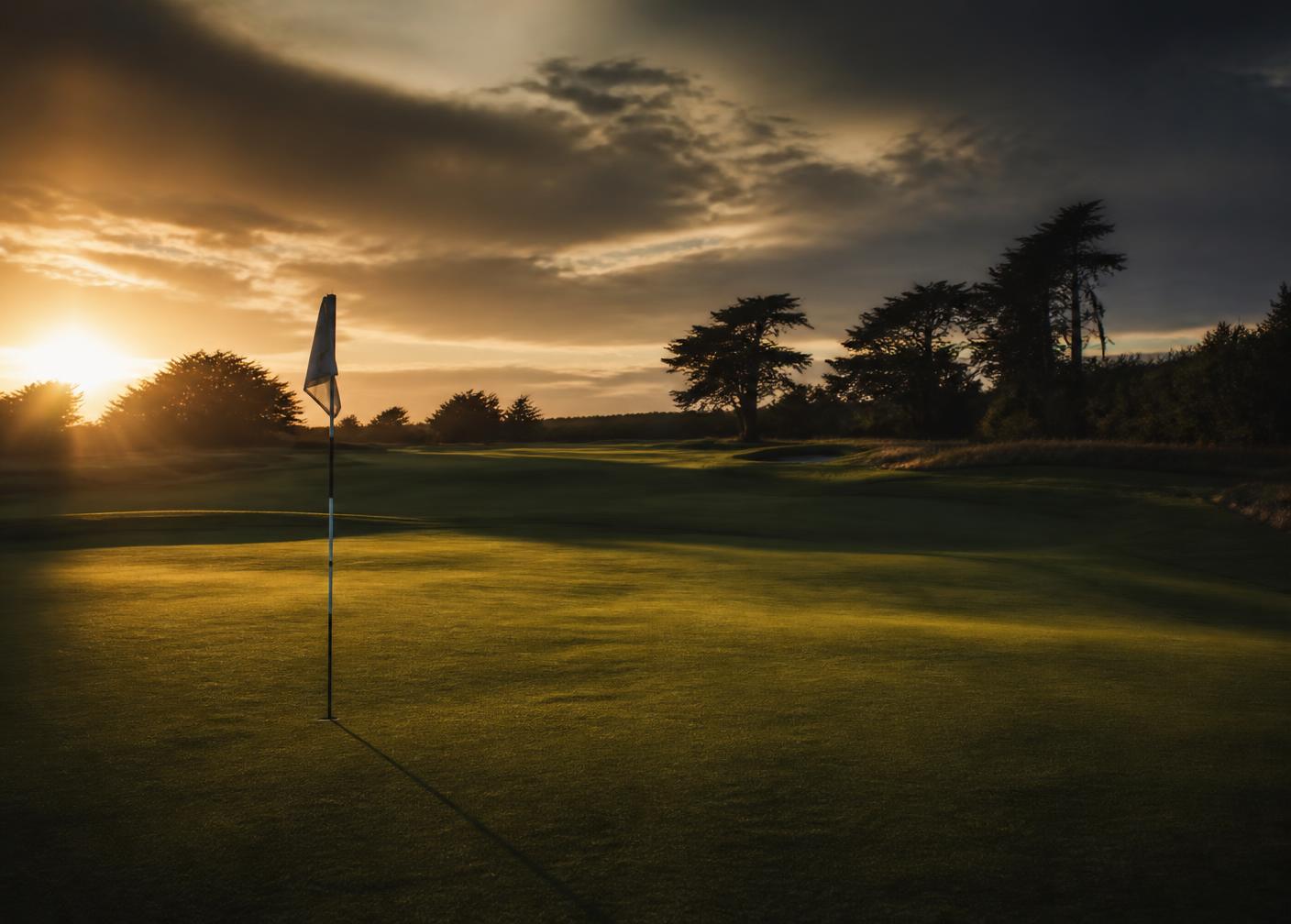 Golf green with a flagstick at golden hour
